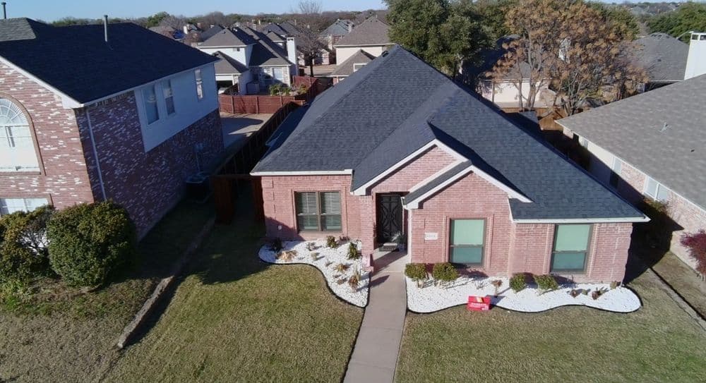 Brick home with landscaped front yard and new roof in suburban neighborhood.