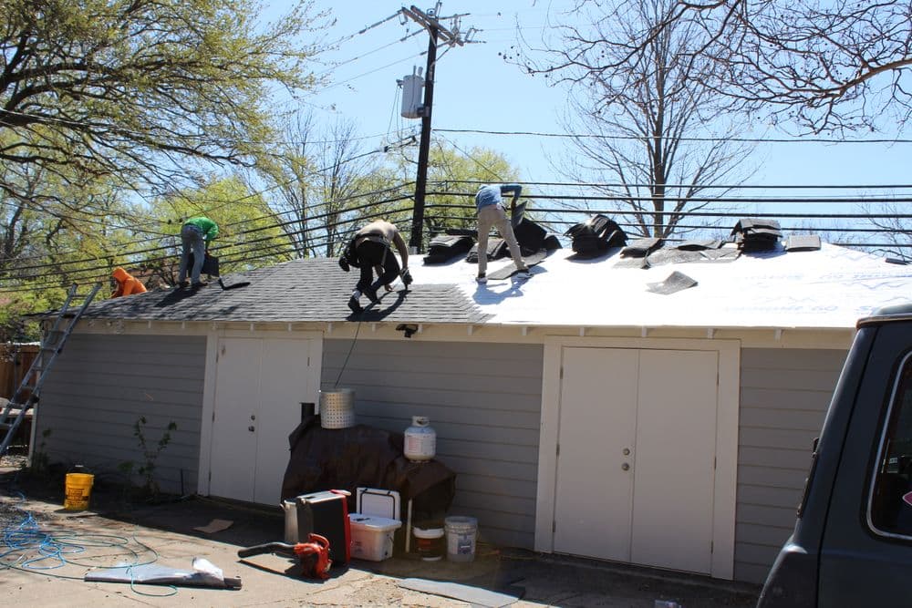 Workers installing a new roof on a residential building on a sunny day.