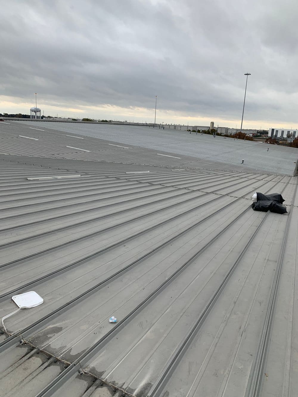 Industrial rooftop view under cloudy skies, showcasing metal roofing and distant cityscape.