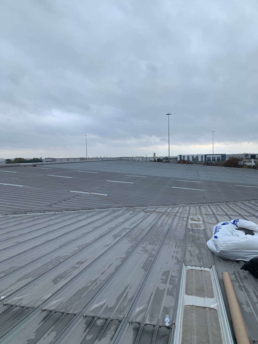 Flat industrial rooftop under cloudy sky with storage materials nearby.