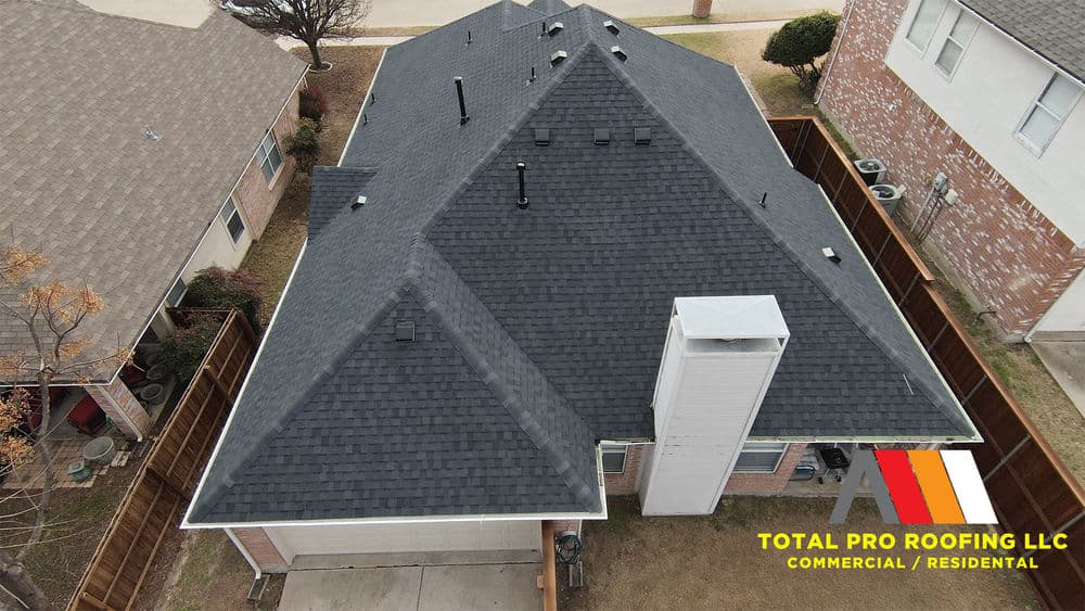Aerial view of a residential home with a new black shingle roof by Total Pro Roofing LLC.