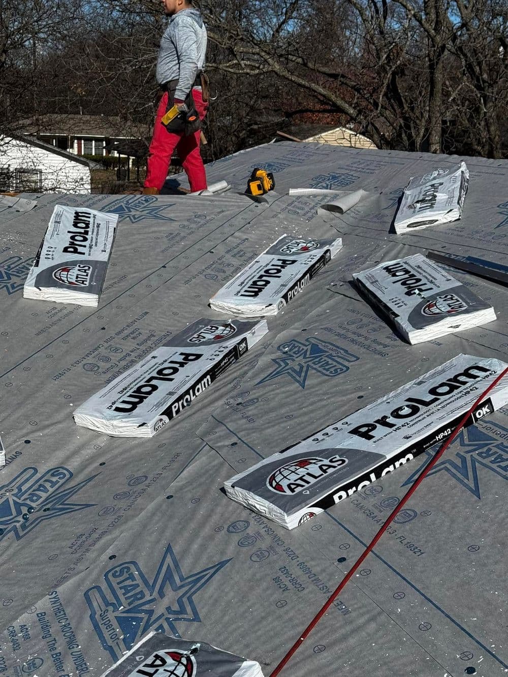 Worker installing roofing materials on a residential roof with Prolam insulation.