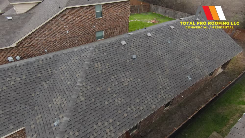 Aerial view of a well-maintained residential roof with shingles and skylights. Total Pro Roofing logo.