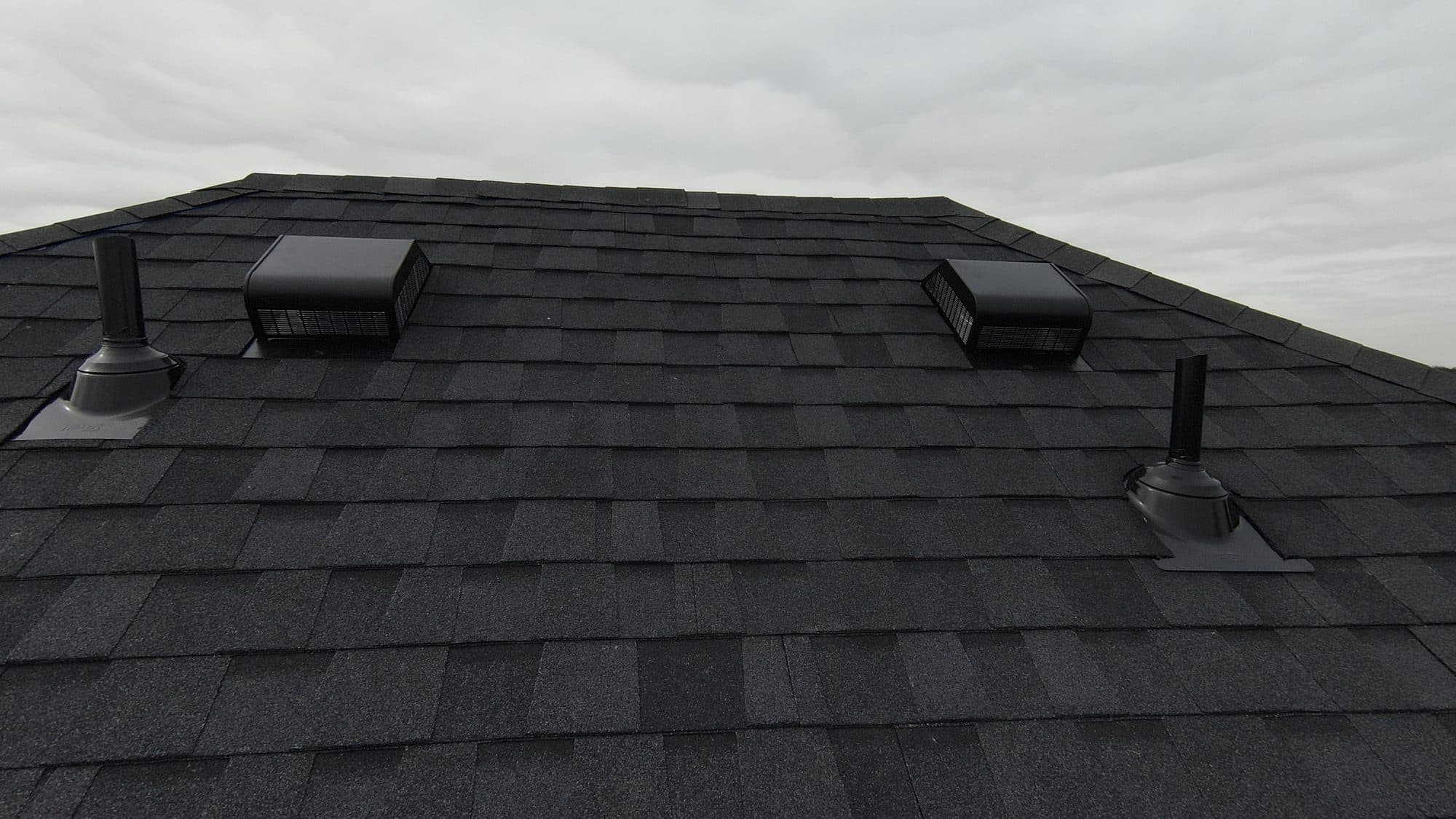 Close-up of dark architectural shingles and roof vents during a roof inspection in Plano, TX