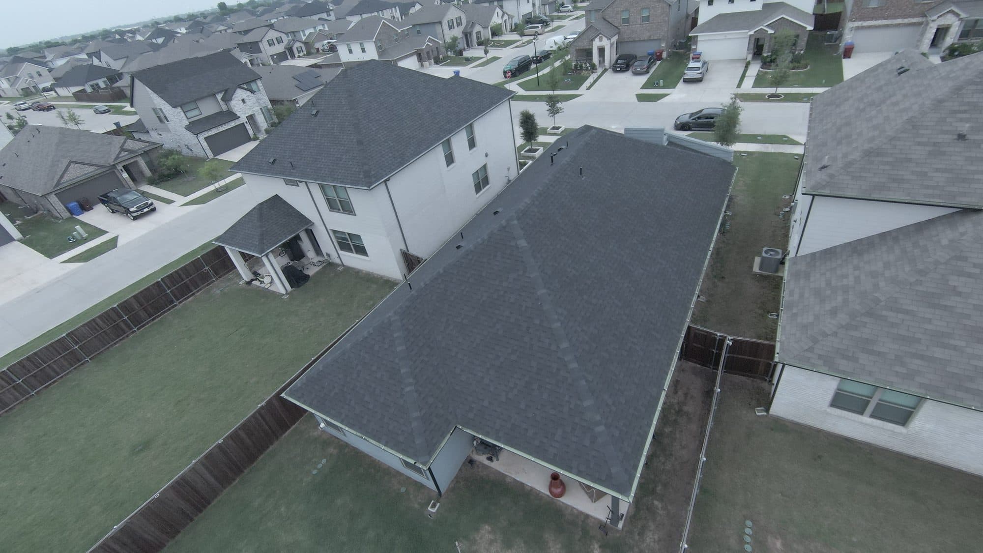 Aerial view of a new shingle roof on a home in a Royse City, TX neighborhood after storm repairs