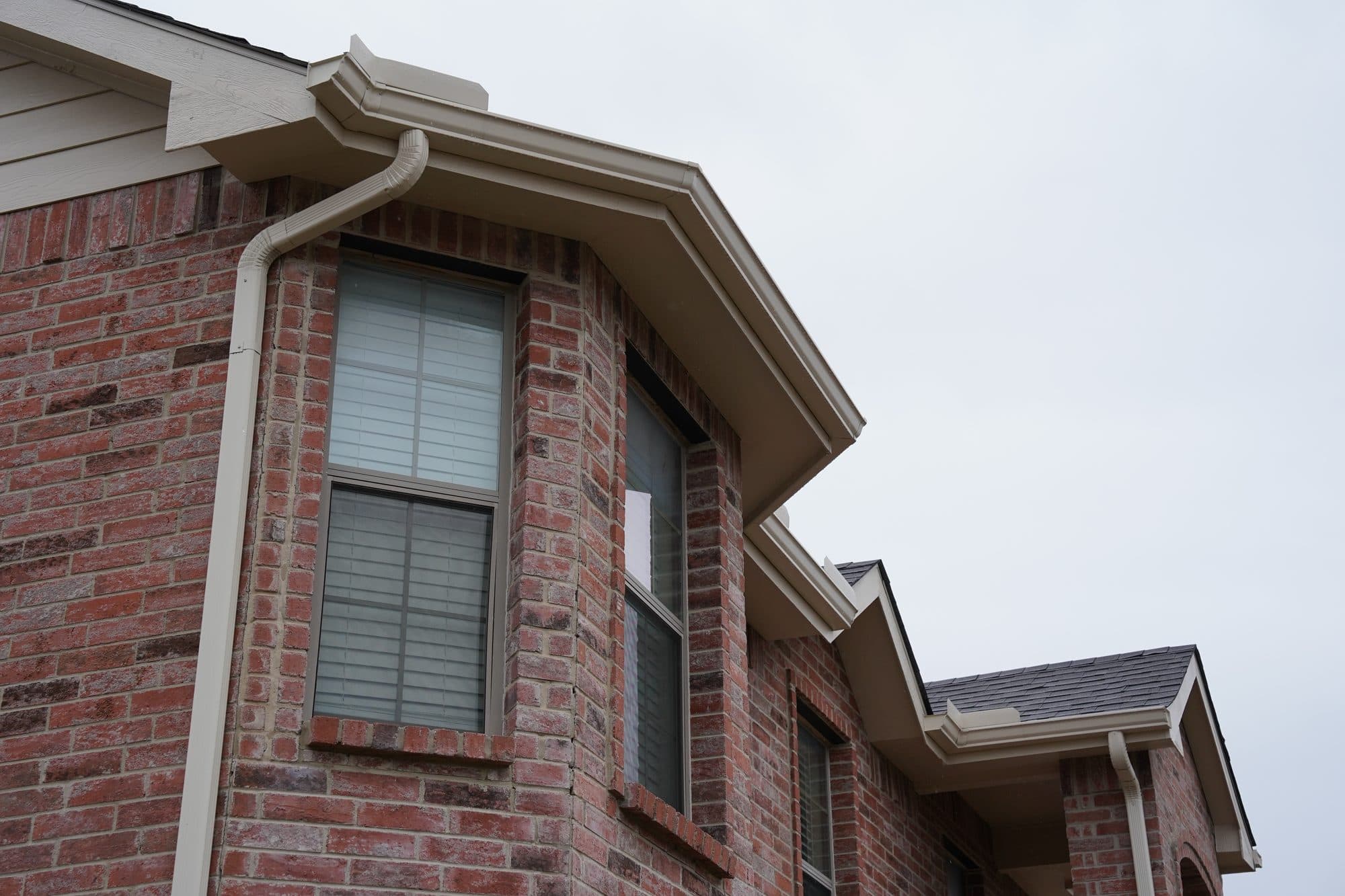 Seamless gutters and downspout on a two-story red brick home in the DFW area